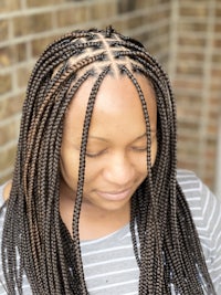 a woman with braided hair in front of a brick wall