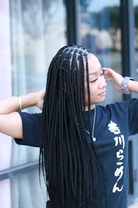 a woman with braided hair posing in front of a building